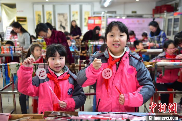 圖為小學(xué)生展示繡制好的2022年北京冬奧會吉祥物“冰墩墩”形象?！∮髟屏?攝