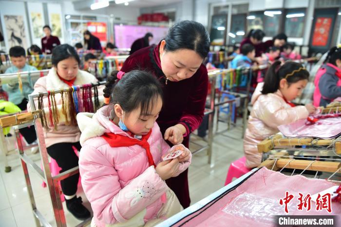 江西省級非遺豫章繡傳承人手把手指導(dǎo)小學(xué)生繡制2022年北京冬奧會吉祥物“冰墩墩”形象。　喻云亮 攝