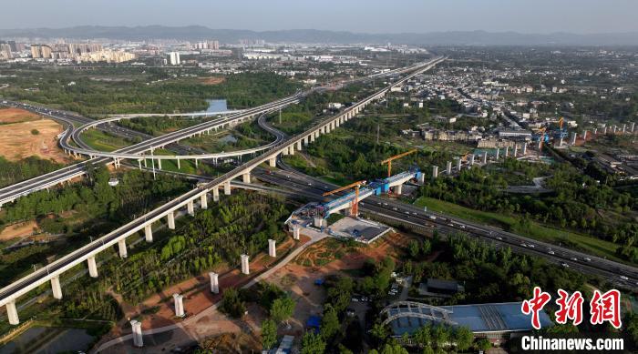 航拍正在建設(shè)的跨越成都繞城高速公路連續(xù)梁施工現(xiàn)場，旁邊依次為已運(yùn)營的成渝高速鐵路和機(jī)場高速公路?！⒅铱?攝