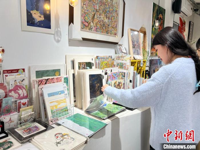 圖為藝術(shù)品商店內(nèi)，顧客挑選插畫作品?！＄婌?攝