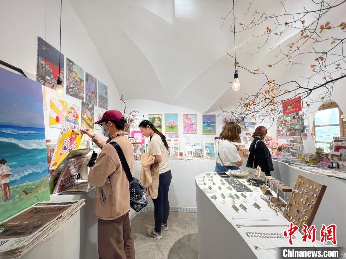 圖為藝術(shù)品商店內(nèi)，顧客挑選插畫作品?！＄婌?攝