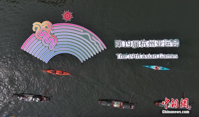 資料圖為烏篷船和皮劃艇從杭州亞運會標(biāo)識前劃過。王剛 攝