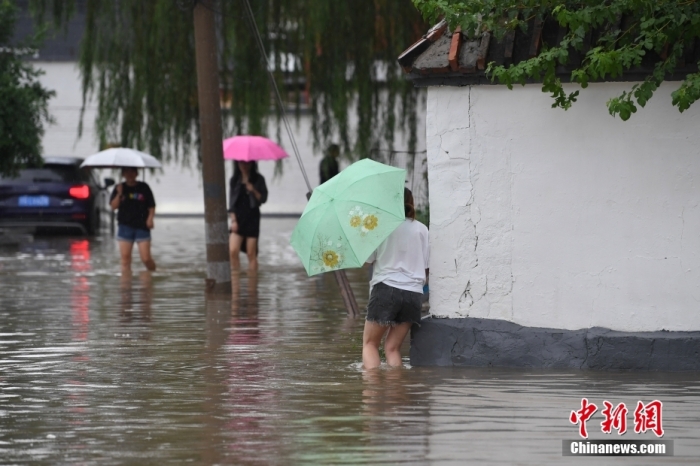 7月31日，市民行走在雨中的北京房山區(qū)瓦窯頭村。北京市氣象臺(tái)當(dāng)日10時(shí)發(fā)布分區(qū)域暴雨紅色預(yù)警信號(hào)。北京市水文總站發(fā)布洪水紅色預(yù)警，預(yù)計(jì)當(dāng)日12時(shí)至14時(shí)，房山區(qū)大石河流域?qū)⒊霈F(xiàn)紅色預(yù)警標(biāo)準(zhǔn)洪水。<a target='_blank' href='/'><p  align=