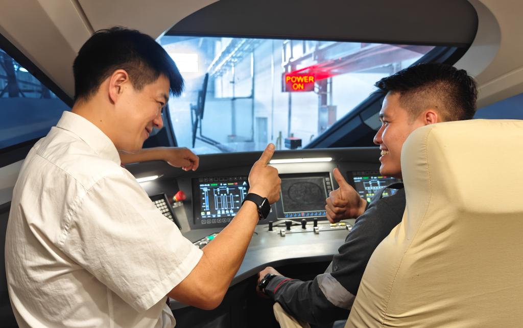 8月25日，在印度尼西亞萬隆的雅萬高鐵德卡魯爾動車所內(nèi)，中國師傅穆振（左）在向印尼火車司機塞蒂亞萬講解動車組出庫前的上電作業(yè)。