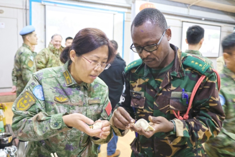 圖為維和官兵與外軍人員共同包餃子。胡光明攝