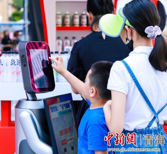 圖為一名小朋友正在和機(jī)器人“志愿者”進(jìn)行互動(dòng)。 沐聞 攝