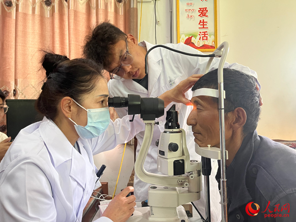 王紅英（左）和團(tuán)隊(duì)成員為達(dá)熱村村民檢查眼睛。人民網(wǎng)記者 杜燕飛攝