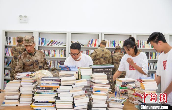 圖為志愿者們和邊防戰(zhàn)士整理圖書?！詵| 攝