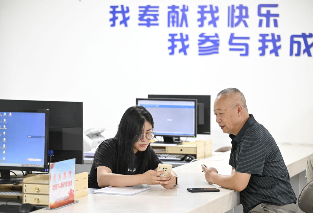 2024年6月20日，在寧夏銀川市金鳳區(qū)長(zhǎng)城花園社區(qū)黨群服務(wù)中心，工作人員幫助居民辦理業(yè)務(wù)。圖片來(lái)源 新華社