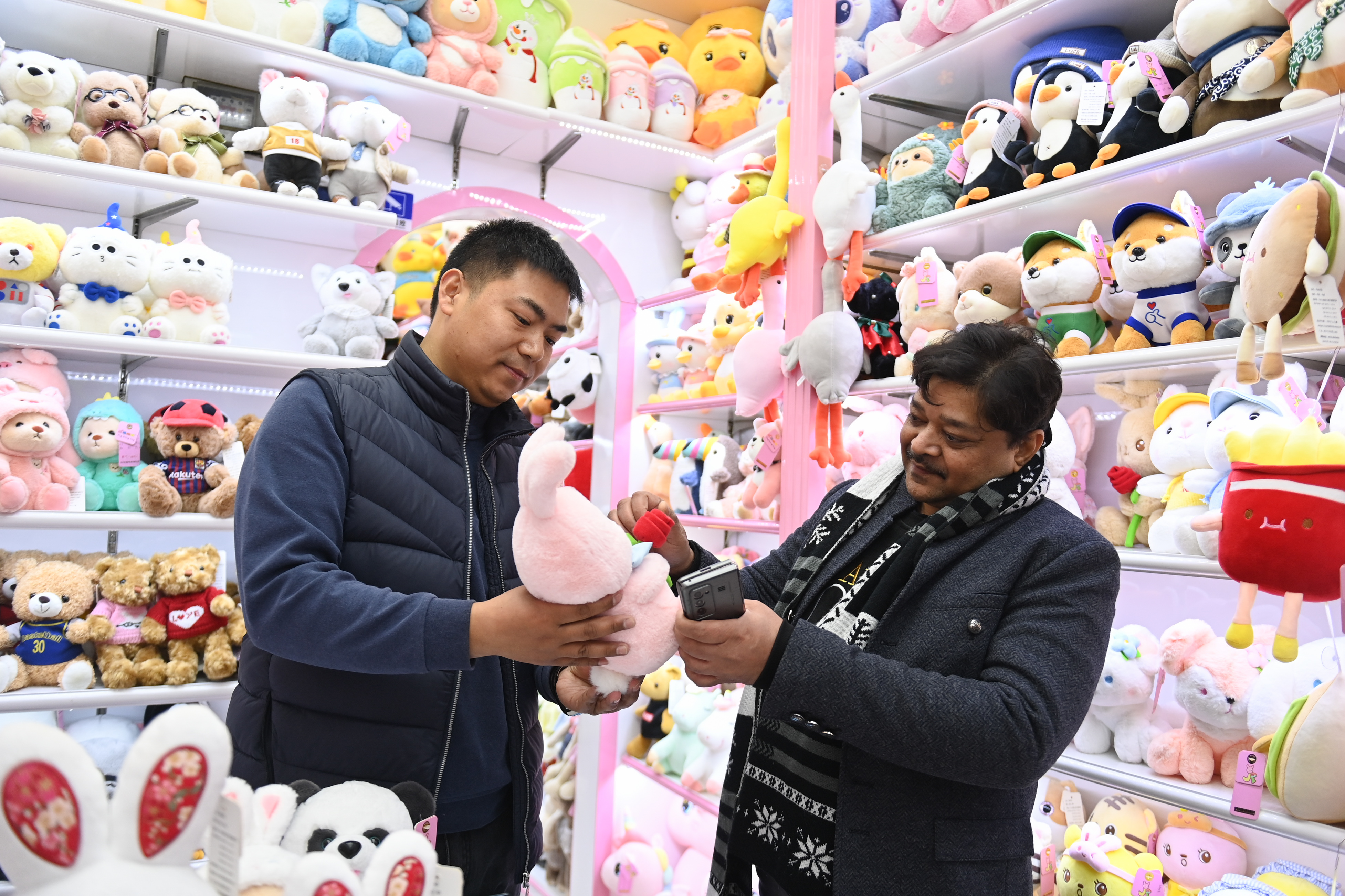 2023年2月2日，來自印度的客商（右）在義烏國(guó)際商貿(mào)城的一家玩具店鋪內(nèi)選購(gòu)。