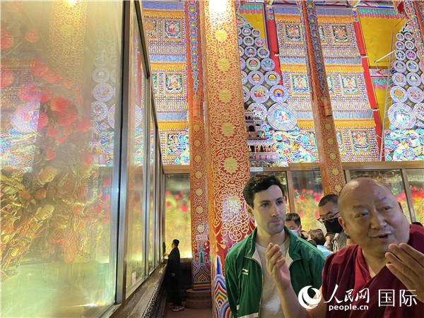 7月25日，省級(jí)非物質(zhì)文化遺產(chǎn)項(xiàng)目塔爾寺酥油花的代表性傳承人朋措堅(jiān)參（右）在塔爾寺酥油花館講解酥油花的制作過程。人民網(wǎng) 謝瑩攝