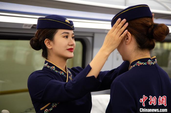 圖為青藏鐵路西格段“復(fù)興號”動車組乘務(wù)員互相整理新制服?！±罾?攝