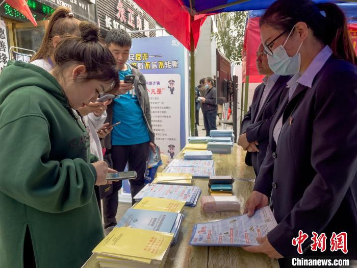 圖為工作人員正在向路過市民介紹國家反詐中心軟件的功能?！≈x牧 攝