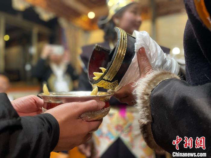 圖為主人在碗中斟滿青稞酒?！∪轿木?攝