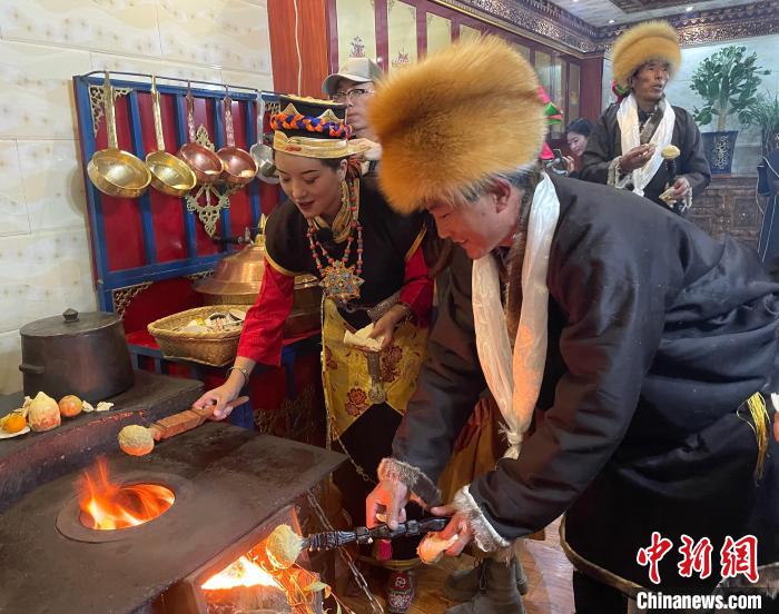 圖為人們在火上烤節(jié)日美食“結(jié)達(dá)”?！∪轿木?攝