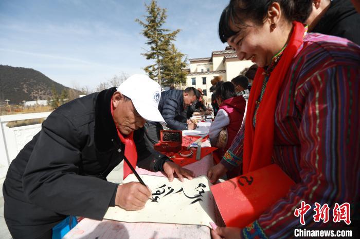 圖為林芝市文聯(lián)書(shū)法家協(xié)會(huì)會(huì)員向民眾贈(zèng)送藏文書(shū)法作品?！埩?攝