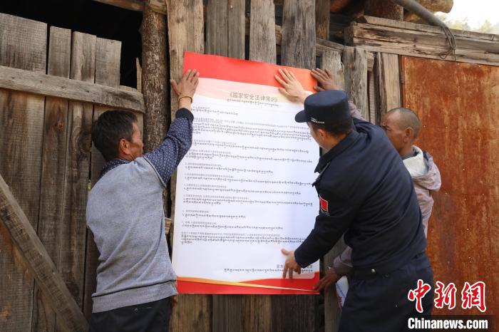 圖為亞?wèn)|邊檢站民警與駐地邊民群眾共同張貼國(guó)家安全知識(shí)教育海報(bào)。　亞?wèn)|邊檢站 供圖