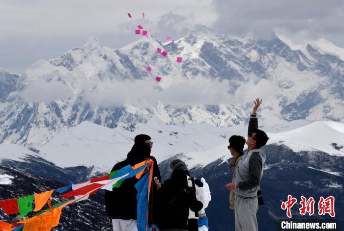 圖為5月14日，游客在西藏林芝色季拉山觀景臺拋灑“隆達(dá)”(風(fēng)馬旗，藏族民眾的一種祈福方式)。　李林 攝
