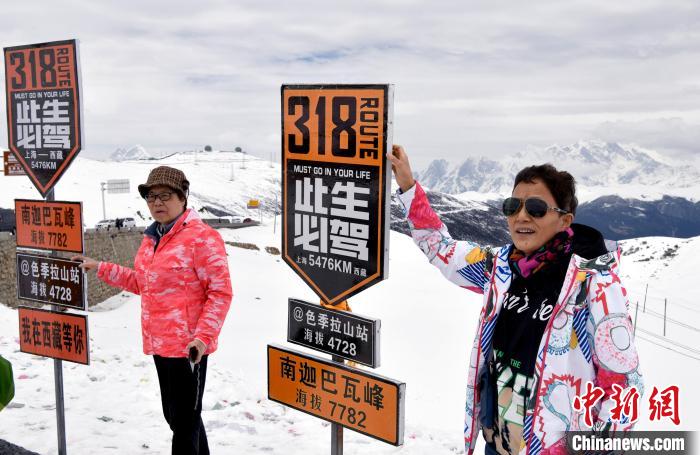 圖為5月14日，西藏林芝色季拉山觀景臺，游客與南迦巴瓦峰合影。　李林 攝